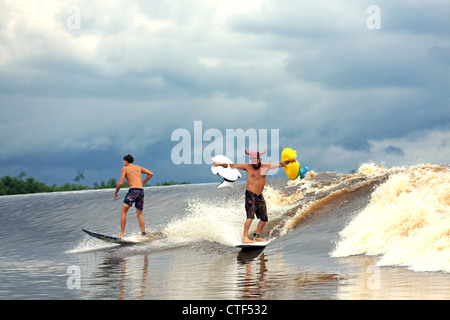 Zwei Surfer Surfen einen Fluss Gezeiten Bohrung Welle am Fluss Kampar in Sumatra, auch bekannt als die 7 Geister. Stockfoto