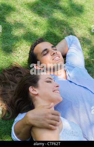 Glücklich schöner junger Mann und Frau in der Liebe, auf dem Rasen im Park liegen und entspannen Stockfoto