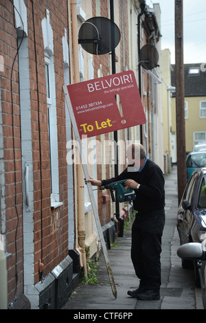 Ein Arbeiter von einer Vermietungsagentur behebt ein Zeichen "Zu lassen", um eine Immobilie in Gloucester UK Stockfoto