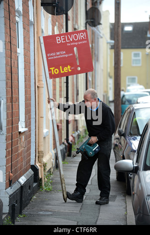 Ein Arbeiter von einer Vermietungsagentur behebt ein Zeichen "Zu lassen", um eine Immobilie in Gloucester UK Stockfoto