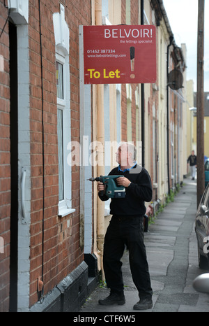 Ein Arbeiter von einer Vermietungsagentur behebt ein Zeichen "Zu lassen", um eine Immobilie in Gloucester UK Stockfoto