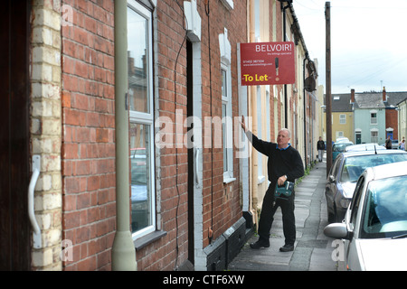 Ein Arbeiter von einer Vermietungsagentur behebt ein Zeichen "Zu lassen", um eine Immobilie in Gloucester UK Stockfoto