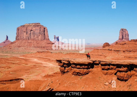 ein Indianer auf einem Pferd vor einem roten Felsformationen in Monument Valley Stockfoto