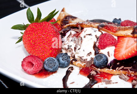 Eis in frischen Pan Cake mit gemischten Früchten auf schwarzem Hintergrund Stockfoto