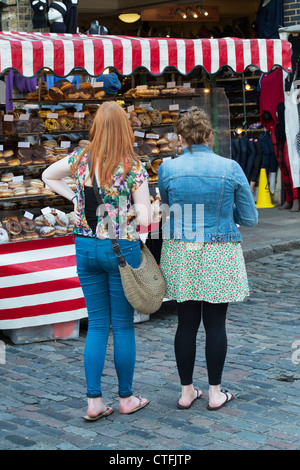 Zwei Mädchen Donuts auf einen Donut-Stand zu betrachten. Camden. London Stockfoto
