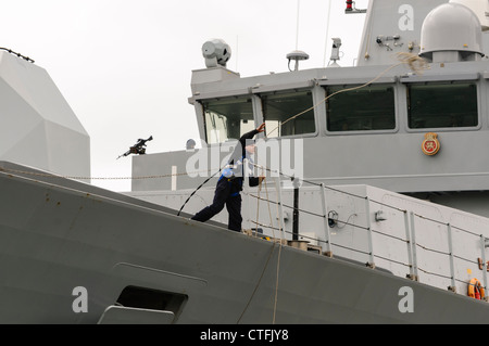 Matrose auf königliche Marine Art 45 Zerstörer HMS Dragon wirft ein Blei-Seil zu dockers Stockfoto