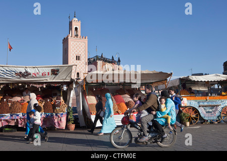 Marokko, genannt Marrakesch Platz Djemaa El Fna. Familie auf dem Motorrad vor Nüssen und trockenen Früchten Verkäufer. Stockfoto