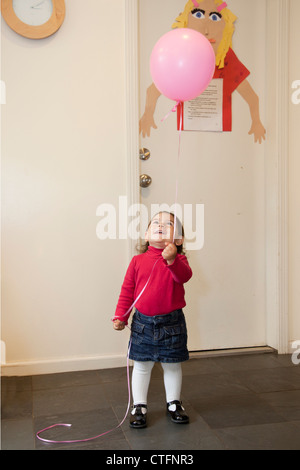 Ein kleines Mädchen in das Haus einen Ballon halten. Stockfoto