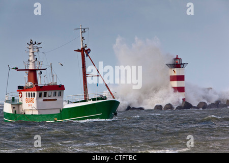 Die Niederlande, IJmuiden, Sturm. Wellen gegen Leuchtturm oder Leuchtfeuer. Schiff. Stockfoto