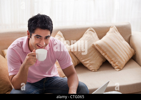 Porträt von gutaussehenden Mann Kaffeetrinken mit laptop Stockfoto