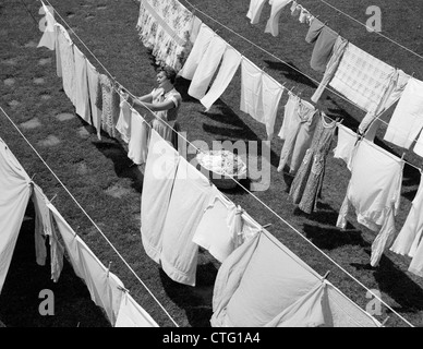 1950ER JAHRE HAUSFRAU HÄNGENDE WÄSCHE IM HINTERHOF Stockfoto