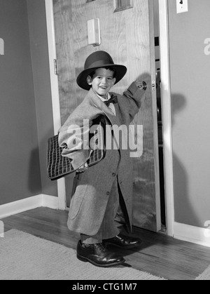 1950ER JAHRE JUNGE GEKLEIDET IN VATERS KLEIDUNG MIT ATTACHÉ CASE ÖFFNENDE TÜR DES HAUSES, WENN ZUR ARBEIT GEHEN Stockfoto