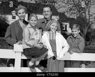 1960ER JAHRE PORTRAIT LÄCHELND FAMILIE VATER MUTTER 2 TÖCHTER SOHN VON WEIßEN ZAUN VOR S HAUS IM HERBST Stockfoto