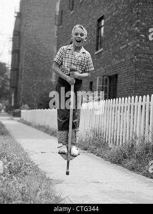 1960ER JAHRE JUNGE AUF POGO STICK ON BÜRGERSTEIG Stockfoto