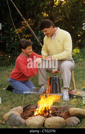 1990ER JAHREN VATER UND SOHN AM LAGERFEUER AN ANGELRUTE UND FLIEGEN Stockfoto