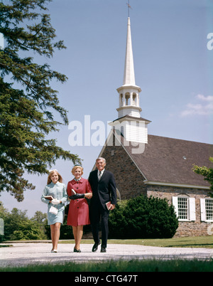 1960ER JAHREN LÄCHELND FAMILIE VERLASSEN KIRCHE JEDE TRAGENDEN BIBEL Stockfoto