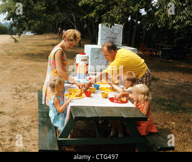 1970ER JAHRE FAMILIE ESSEN AN OUTDOOR-PICKNICK-TISCH Stockfoto