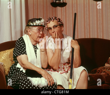 1960ER JAHRE ZWEI SENIOR ÄLTERE FRAUEN SITZEN AUF DEM SOFA KLATSCH Stockfoto