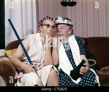 1960ER JAHRE ZWEI SENIOR ÄLTERE FRAUEN SITZEN AUF DEM SOFA KLATSCH Stockfoto