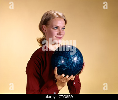 1960ER JAHRE JUNGE LÄCHELND BLONDE FRAU MIT BOWLING-KUGEL TRAGEN ROTE HEMD ÜBER SCHÜSSEL Stockfoto