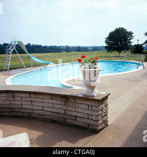 1960ER JAHRE NIERE GEFORMTEN SWIMMINGPOOL TERRASSE SPRUNGBRETT LEITER STEINMAUER MIT ÜBERTOPF Stockfoto