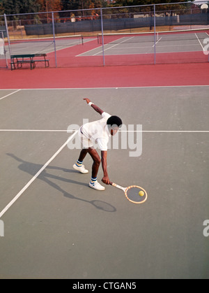 1970ER JAHRE MANN AFRIKANISCH-AMERIKANISCHEN SPIELEN TENNIS SCHIEFEN OVER ÜBER ZU GERINGE RÜCKHAND HIT BALL Stockfoto