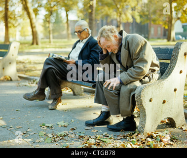 1960S 1970S SENIOR OBDACHLOSE MÄNNER SITZEN AUF BANK IM STADTPARK Stockfoto