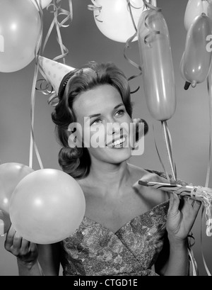 1960S 1950S FRAU IN PARTY KLEID LÄCHELND HOLDING BALLON UND NOISE MAKER Stockfoto