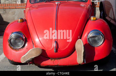 Vorderansicht der alten rot bemalten VW Käfer Oldtimer mit Schuhen auf Vorderseite neben Scheinwerfer Ceredigion Wales UK Stockfoto