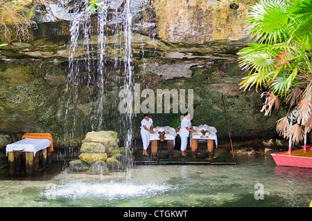 Besucher nach Xcaret genießen Sie eine Massage in einer Höhle hinter einem Wasserfall. Riviera Maya, Yucatan, Mexiko. Stockfoto