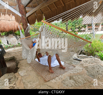 Frau genießt Massage von Maya Mann beim liegen in einer Hängematte im Xcaret, einen Vergnügungspark in Riviera Maya, Yucatan, Mexiko. Stockfoto