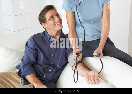 Kaukasische Frau die Mann die Blutdruckmessung Stockfoto