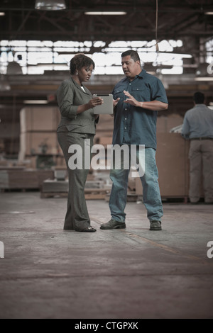 Geschäftsfrau im Gespräch mit Arbeiter im Lager Stockfoto