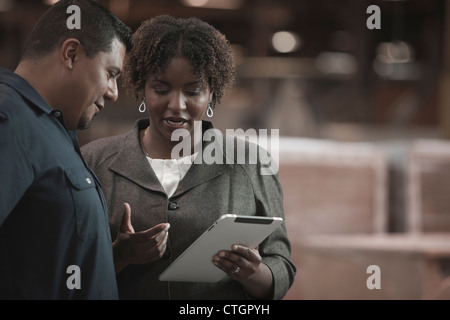 Geschäftsfrau im Gespräch mit Arbeiter im Lager Stockfoto