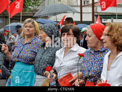 Damen in traditioneller portugiesischer Kleidung mit roten Nelken. 1. Mai: Demonstration zum Arbeitstag in Lissabon, Portugal Stockfoto