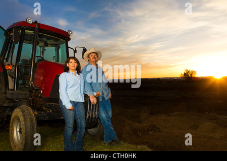 Hispanische paar stehen in der Nähe von Traktor auf Bauernhof Stockfoto