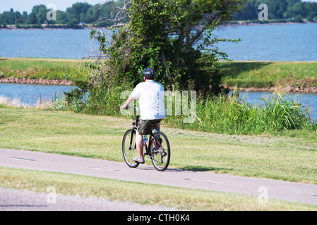 Ein Mann in den 40er reitet sein Fahrrad auf Wanderwegen an einem See in Oklahoma, USA. Stockfoto