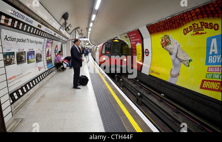 Die Leute auf dem Bahnsteig warten auf den nahenden Zug, den U-Bahnhof Leicester Square, London, England, Großbritannien. Stockfoto