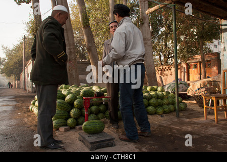 Ein uigurische Mann kauft eine Wassermelone aus einem Stall in Turpan, Xinjiang, China Stockfoto