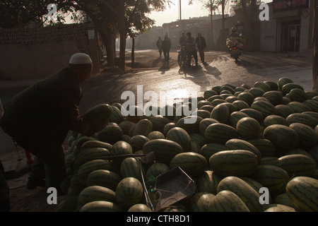 Ein uigurische Mann kauft eine Wassermelone aus einem Stall in Turpan, Xinjiang, China Stockfoto