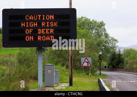 Matrix-Schild an A85 Warnung "nehmen Vorsicht hohes Risiko der Hirsche unterwegs" mit langsamen vor der Kurve und hohen Zaun Crianlarich Scotland UK Stockfoto