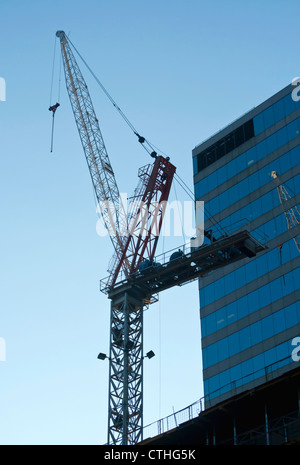 Großen Hochhaus Kran neben Gebäude gegen strahlend blauen Himmel mit Textfreiraum. Stockfoto