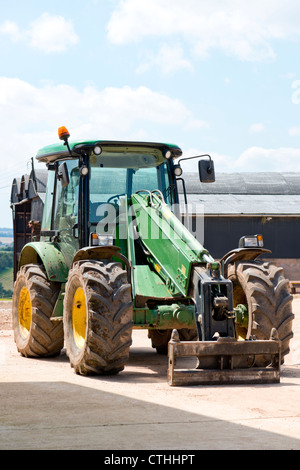 Grüner Traktor auf dem Hof vor einer Scheune abgestellt Stockfoto