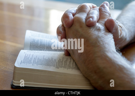 verwitterte alte Mann die Hände im Gebet über aufgeschlagene Bibel Stockfoto