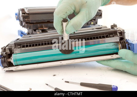 Hände reinigen Tonerkassette mit Pinsel den Staub. Arbeiter Laserdrucker auf einer Werkbank. Drucker-workshop Stockfoto