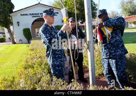 Lt. Bez. Rob Kuffel, links, Stabschef des Naval Surface Warfare Center, Corona Division, befestigt einen Besen an einem Halyard als Department of the Navy Police Officer Victor Reyes und Trouble Failure Reporting (TFR) Liaison Chief Petty Officer Andra Hall Post Colors. Eine Navy Tradition, die bedeutet, "die Feinde aus den Meeren zu weinen", bedeutet der Besen einen sauberen Schwung für NSWC Corona während der Generalkommandantinspektor-Inspektion des Naval Sea Systems in dieser Woche. Stockfoto