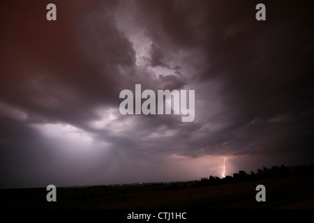 Blitzeinschläge weit entfernt, mit einer Wolkendecke beleuchtet aus innerhalb von anderen Blitz. Regenvorhang auf linken Seite sichtbar. Stockfoto