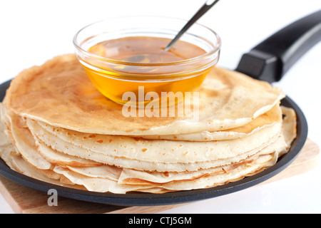 Runde Pfannkuchen in einer Pfanne erhitzen und Honig Nahaufnahme Stockfoto