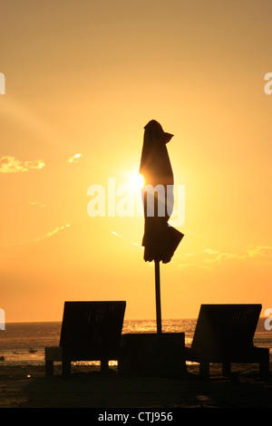 Liegestühle und Sonnenschirm am Strand bei Sonnenuntergang Stockfoto