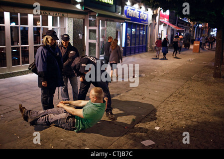 Straße Pastoren helfen einen betrunkenen jungen Mann an einem Samstagabend im Stadtzentrum von Cardiff, Wales, Großbritannien (UK). Stockfoto